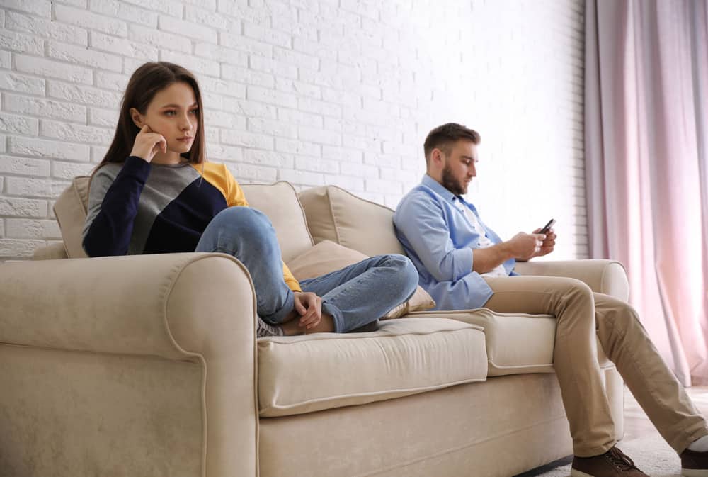 Ung man föredrar smartphone framför sin flickvän hemma