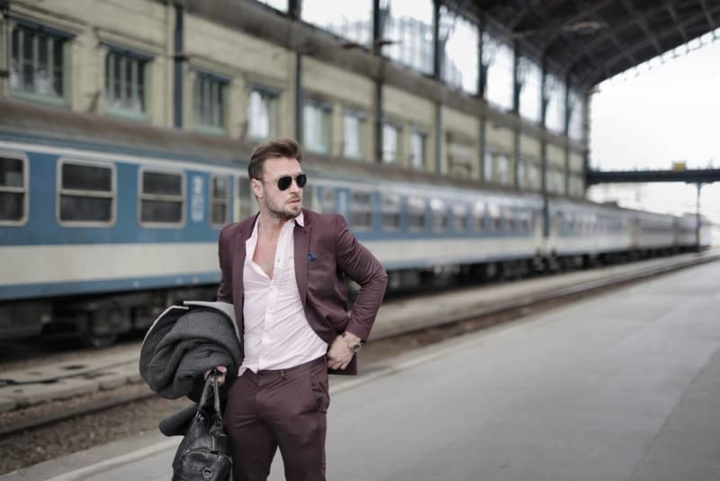 en elegant klädd man med glasögon går till tågstationen