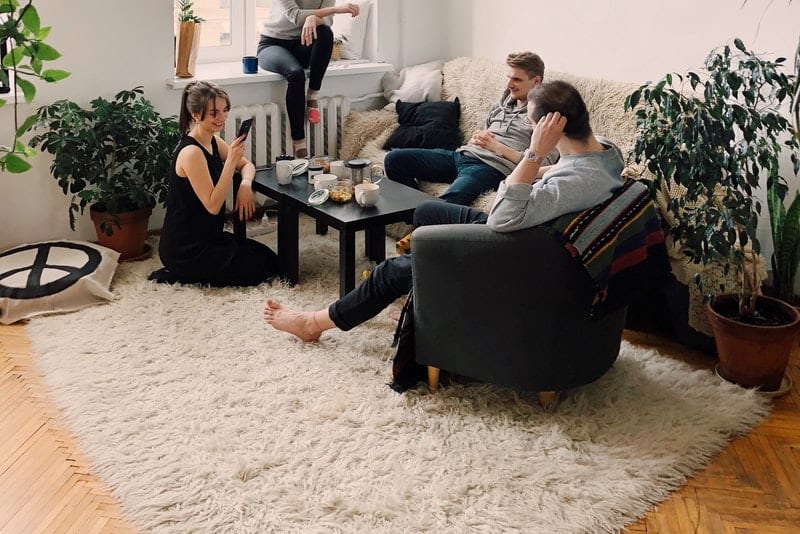 en grupp vänner i vardagsrummet och dricker kaffe