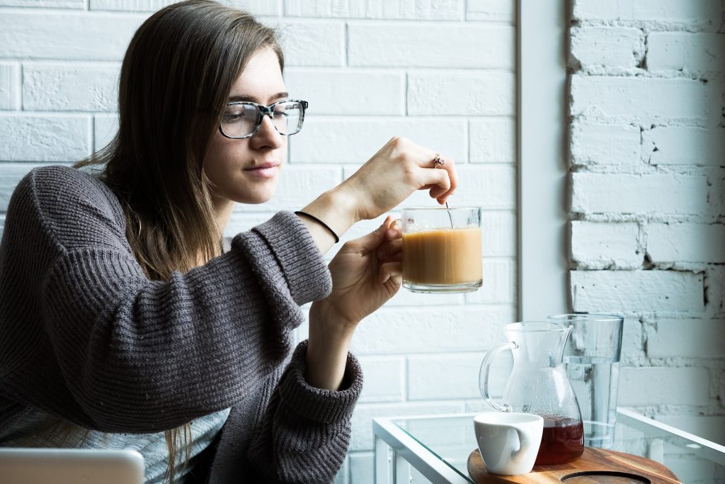 en kvinna sitter vid ett bord och blandar kaffe