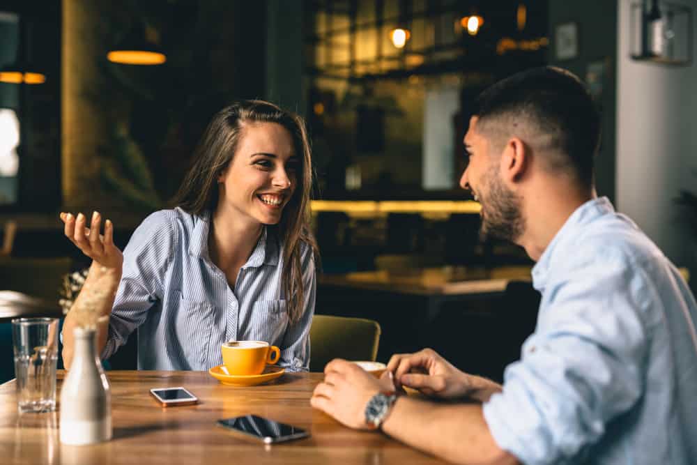 en leende kvinna och en man med skägg vid caféet diskuterar något