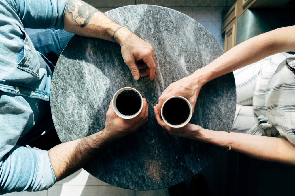 en man och en kvinna pratar vid bordet och dricker kaffe