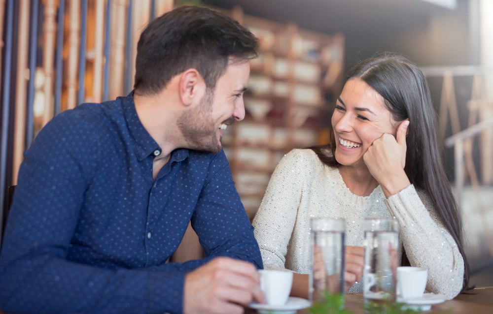 en man och en kvinna sitter och pratar och skrattar
