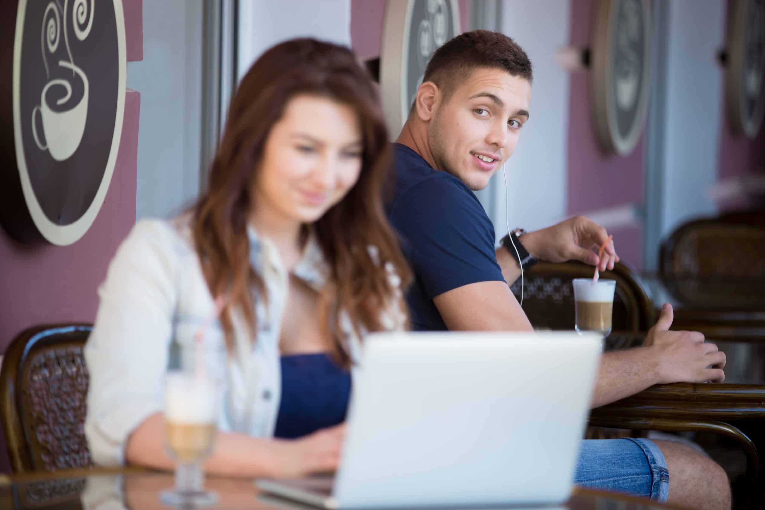en man tittar på en kvinna på ett kafé med ett leende