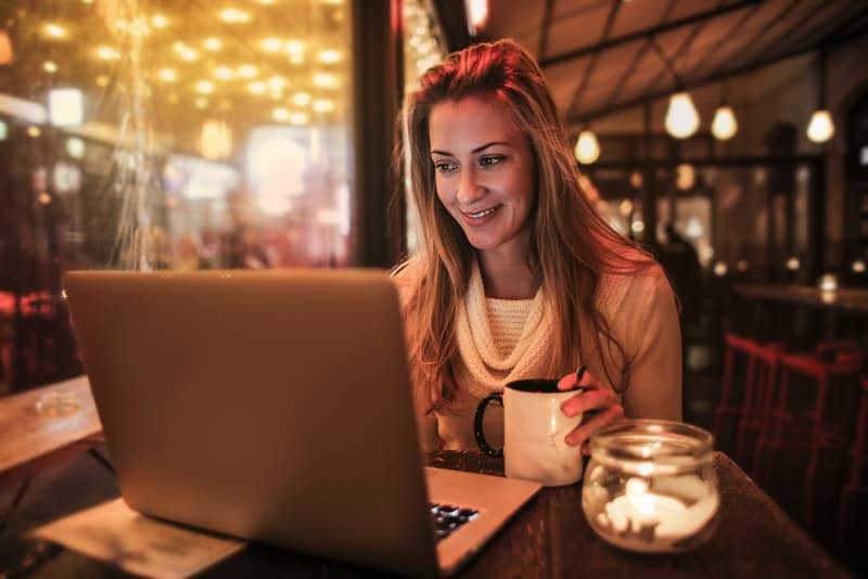 en medelålders kvinna som sitter på ett kafé och arbetar på en bärbar dator