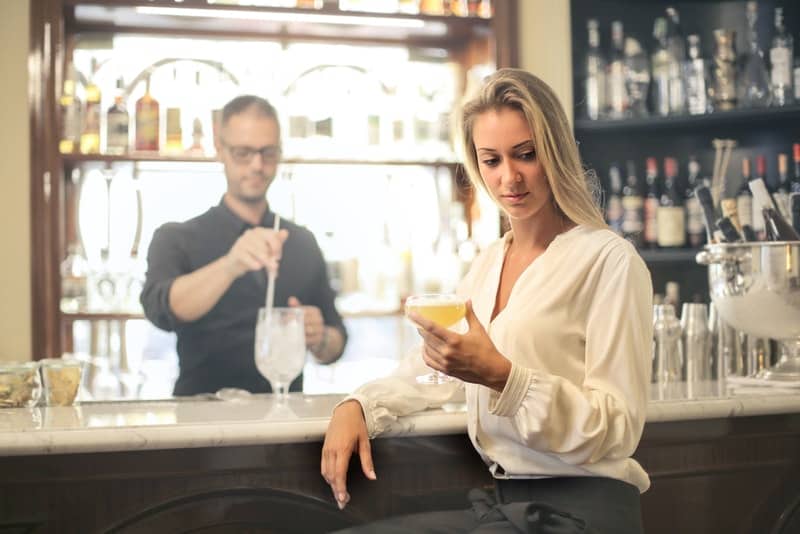 en sorglig kvinna som dricker en cocktail i baren