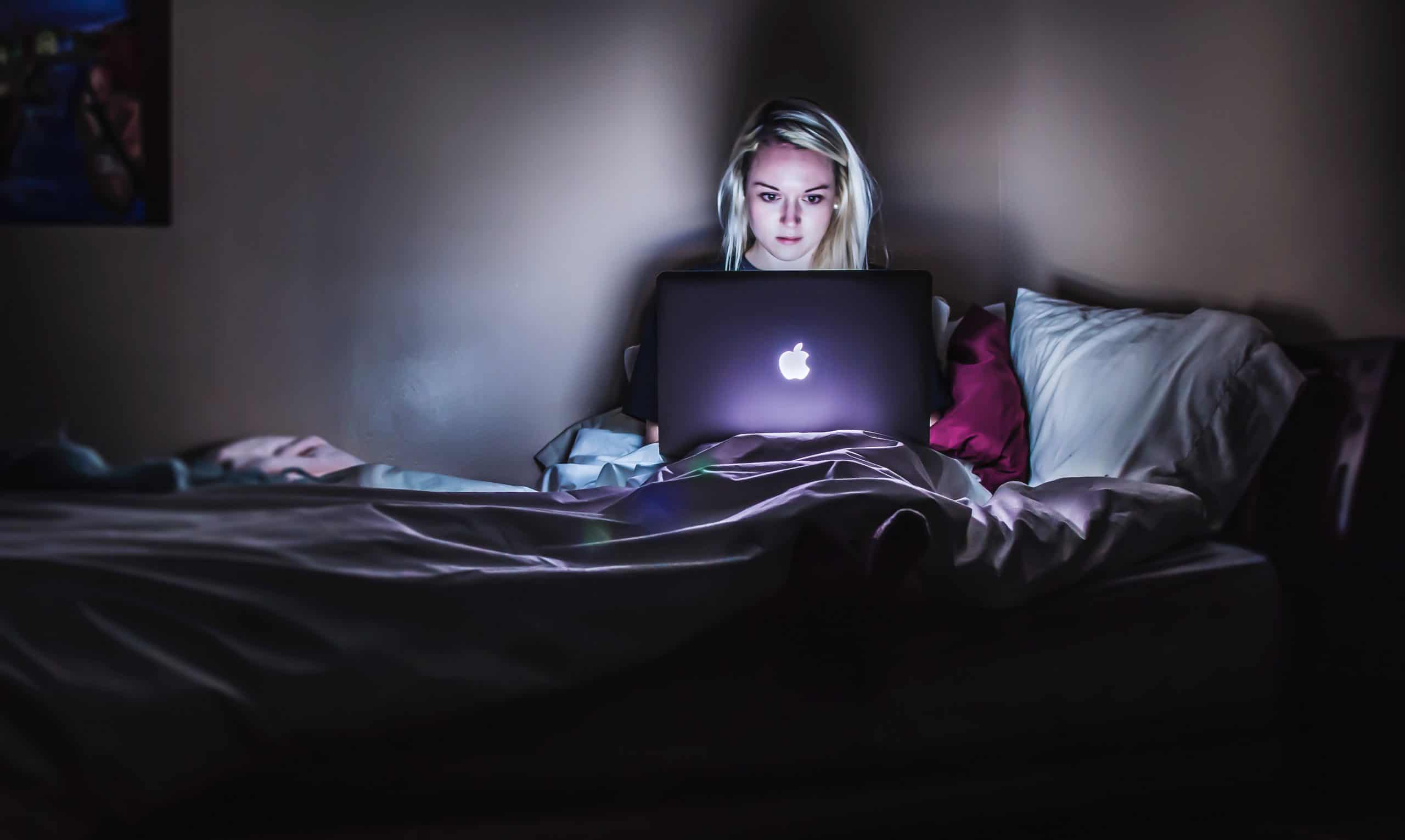 kvinna använder bärbar dator i sängen
