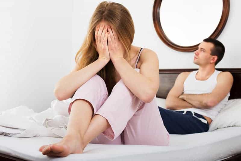 kvinna frustrerad med mannen som sitter på sängen