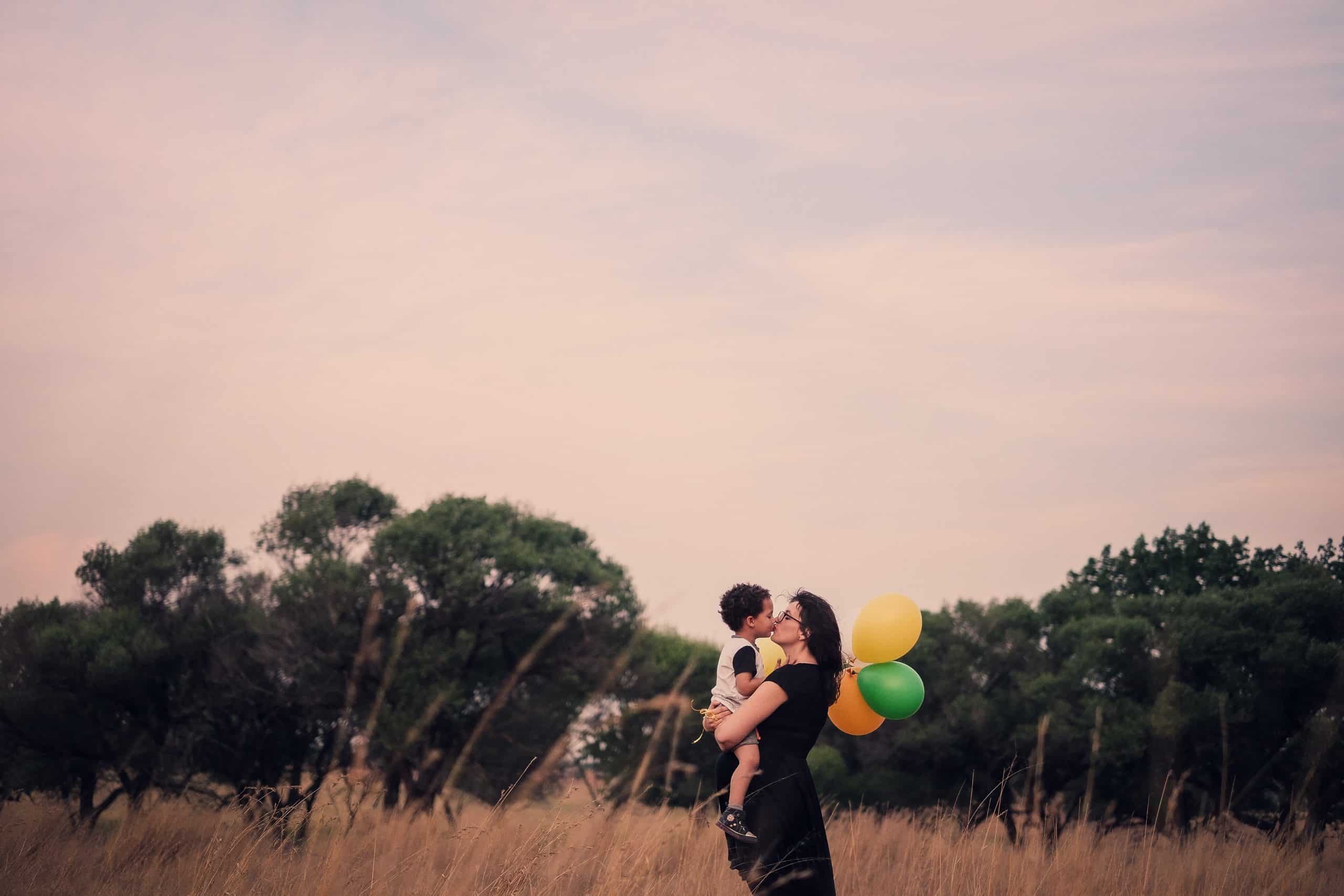 kvinna med ballonger kysser baby