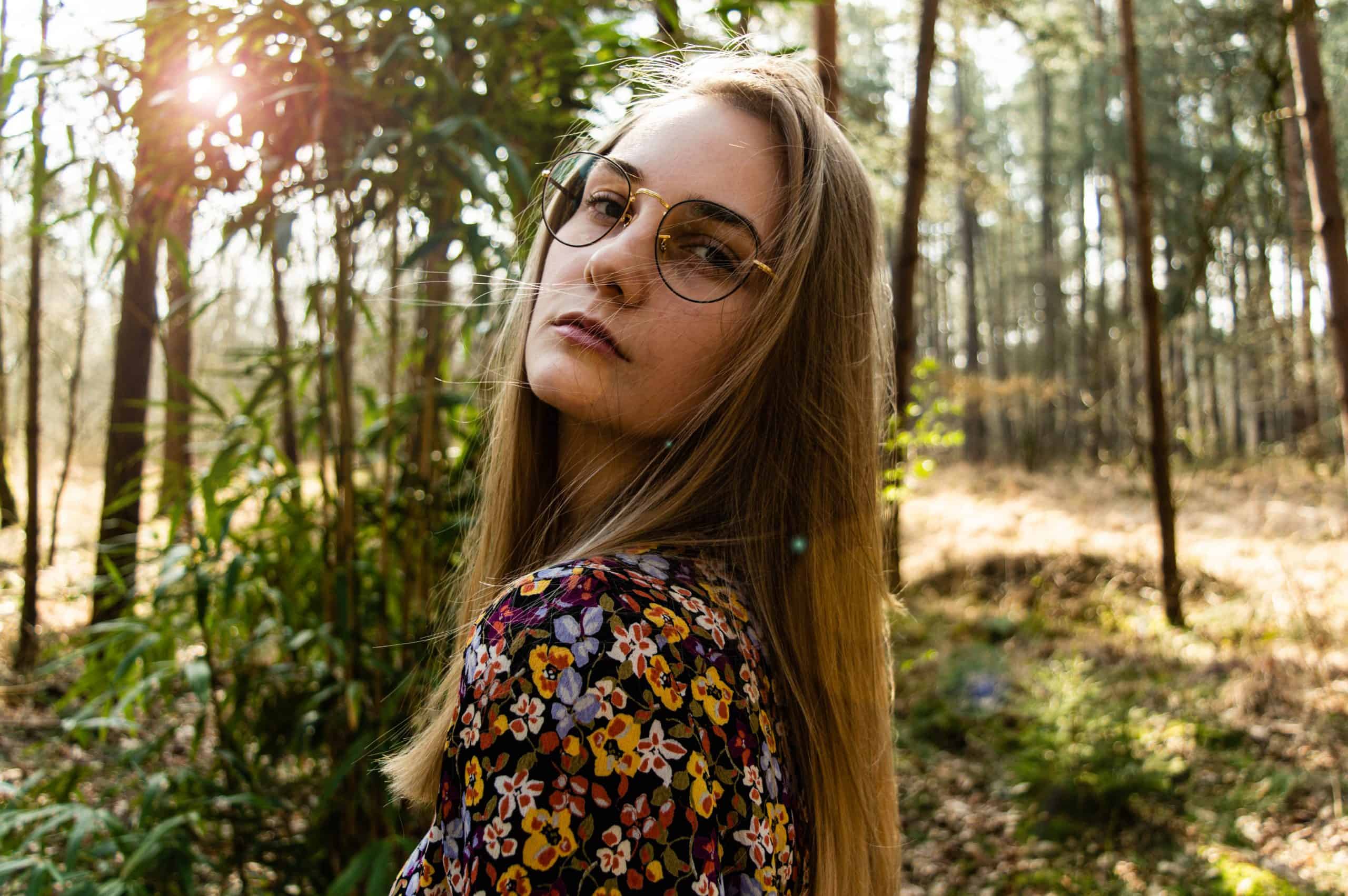 kvinna med glasögon poserar i skogen