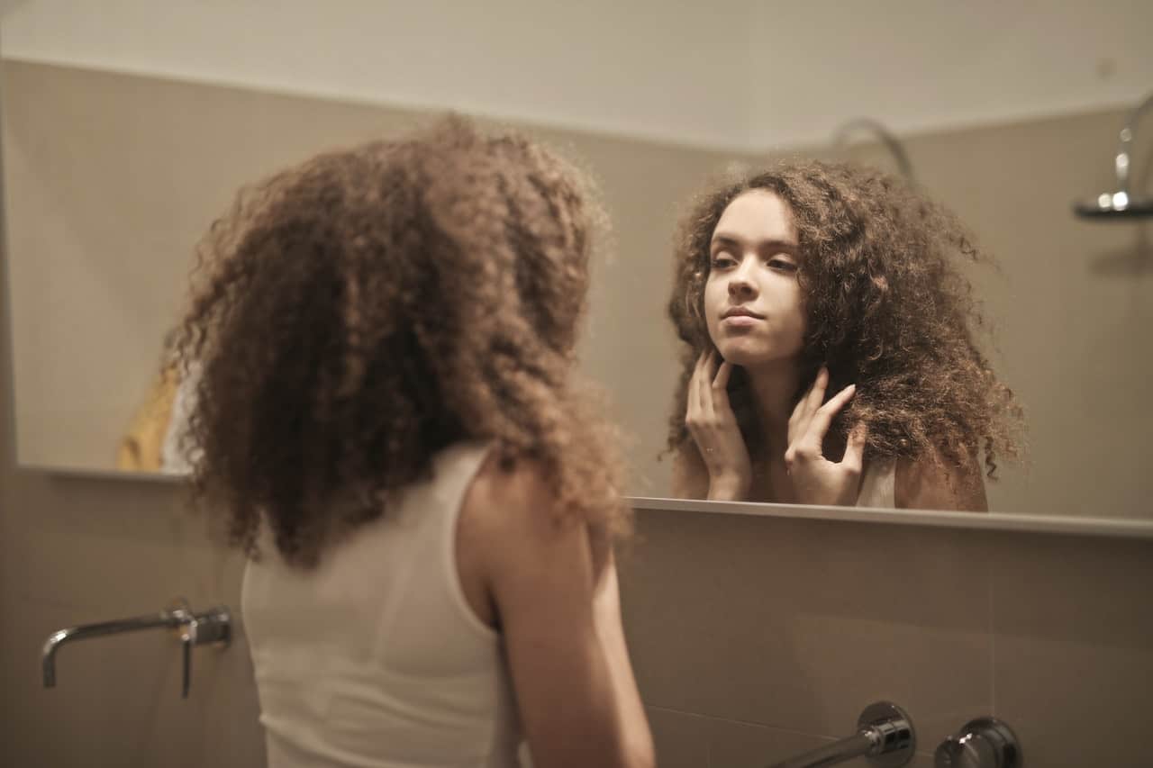 kvinna med lockigt hår tittar på spegeln