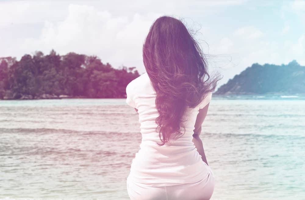 kvinna med svart hår sitter vid stranden