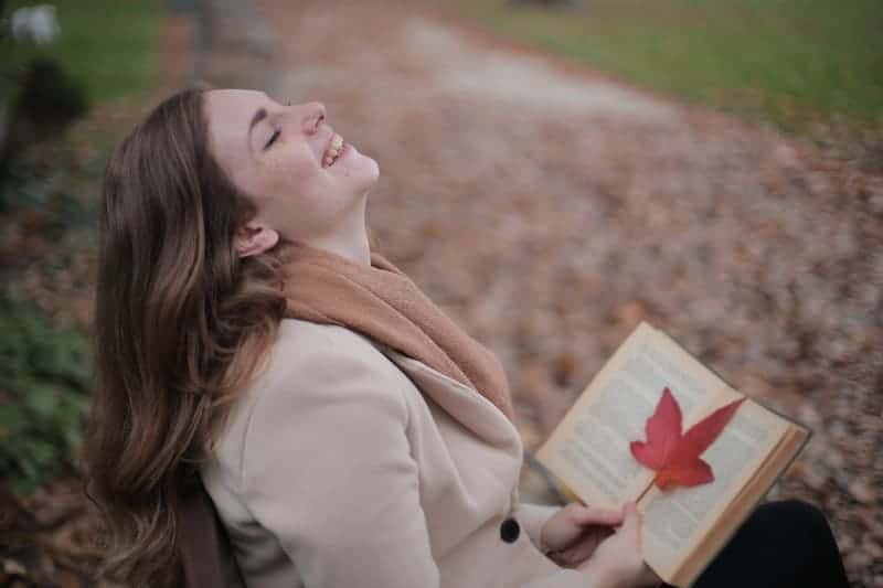 lycklig kvinna som läser i parken