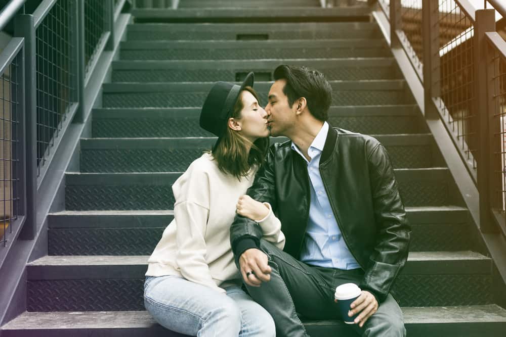 man och kvinna kysser när de sitter på trappan
