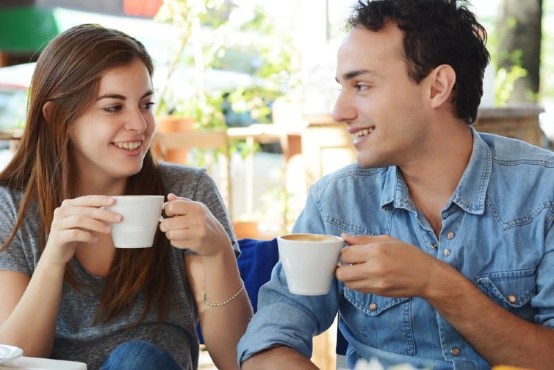 Unga attraktiva par som tycker om ett kaffe på kaféet