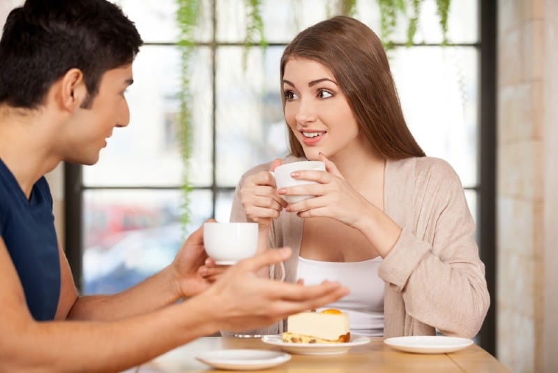 Vackra unga par som tillsammans sitter på restaurangen och dricker kaffe
