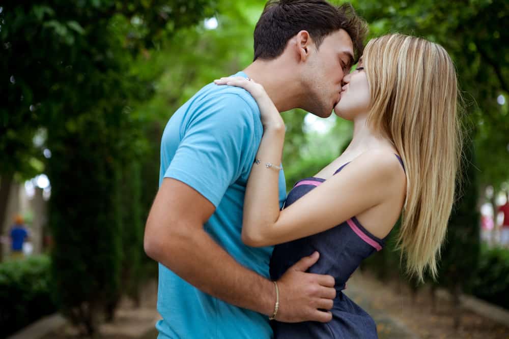 romantiska unga par som kysser och omfamnar i en grön park