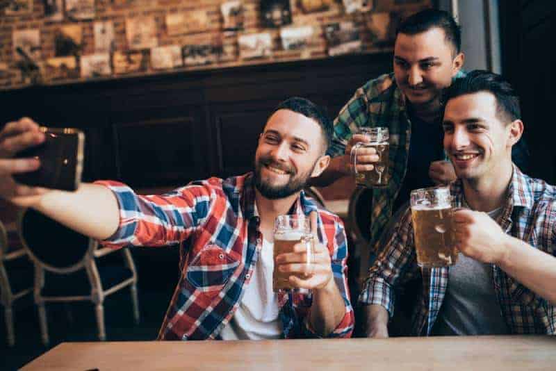 tre manliga vänner som tar selfie medan de håller öl