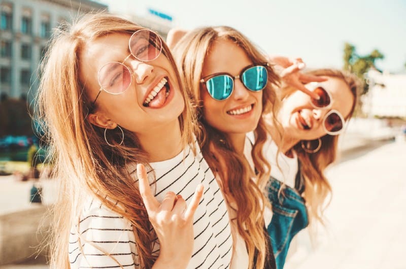 Stående av tre unga vackra leende hipsterflickor i trendiga sommarkläder