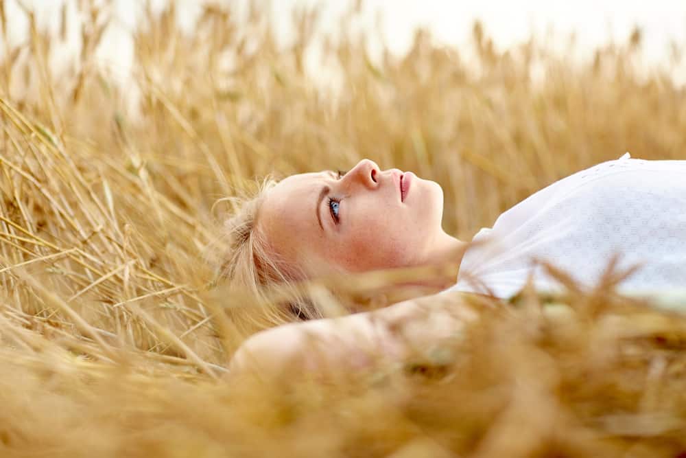 ung kvinna eller tonårsflicka som ligger och drömmer på spannmålsfält