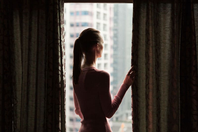 ung kvinna som står vid fönstret