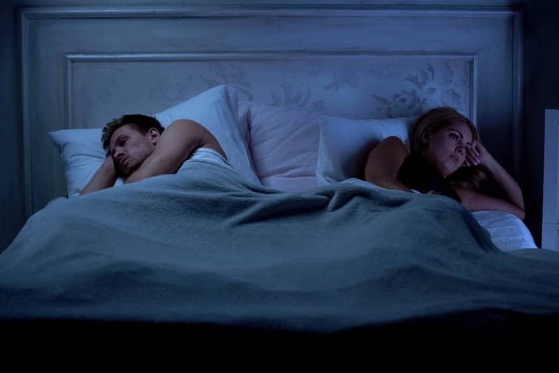 upprörda par som ligger på sängen med rygg mot rygg
