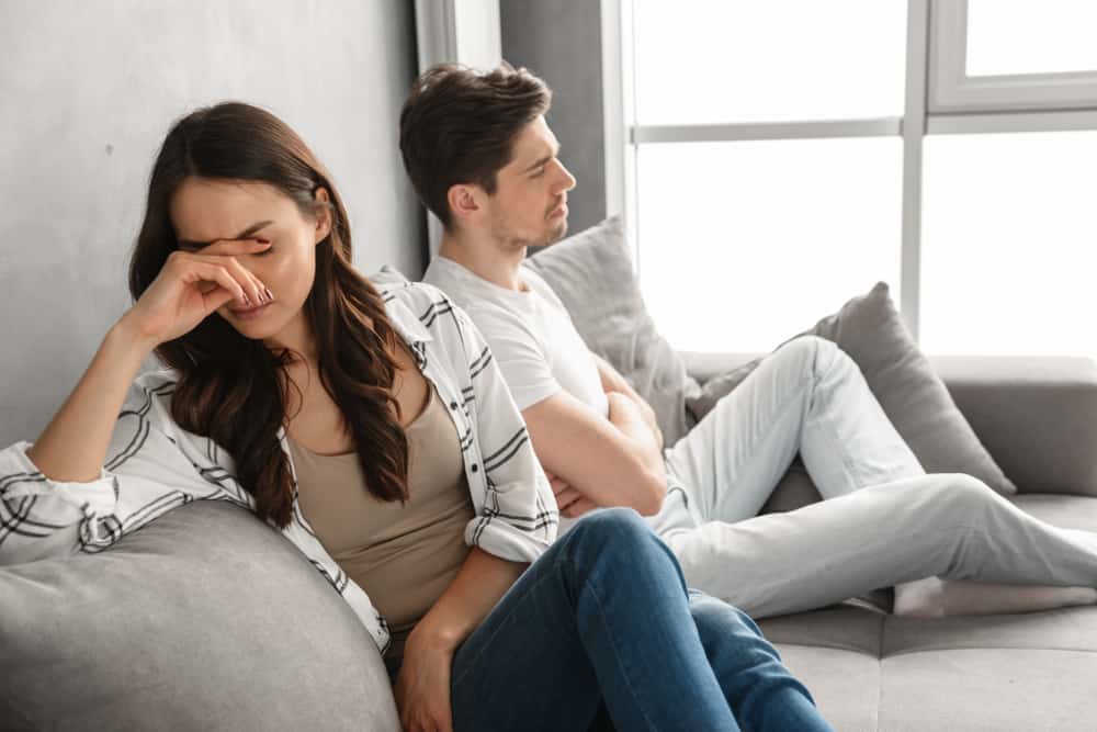 besvikna par som sitter tillsammans på soffan hemma med upprörd look