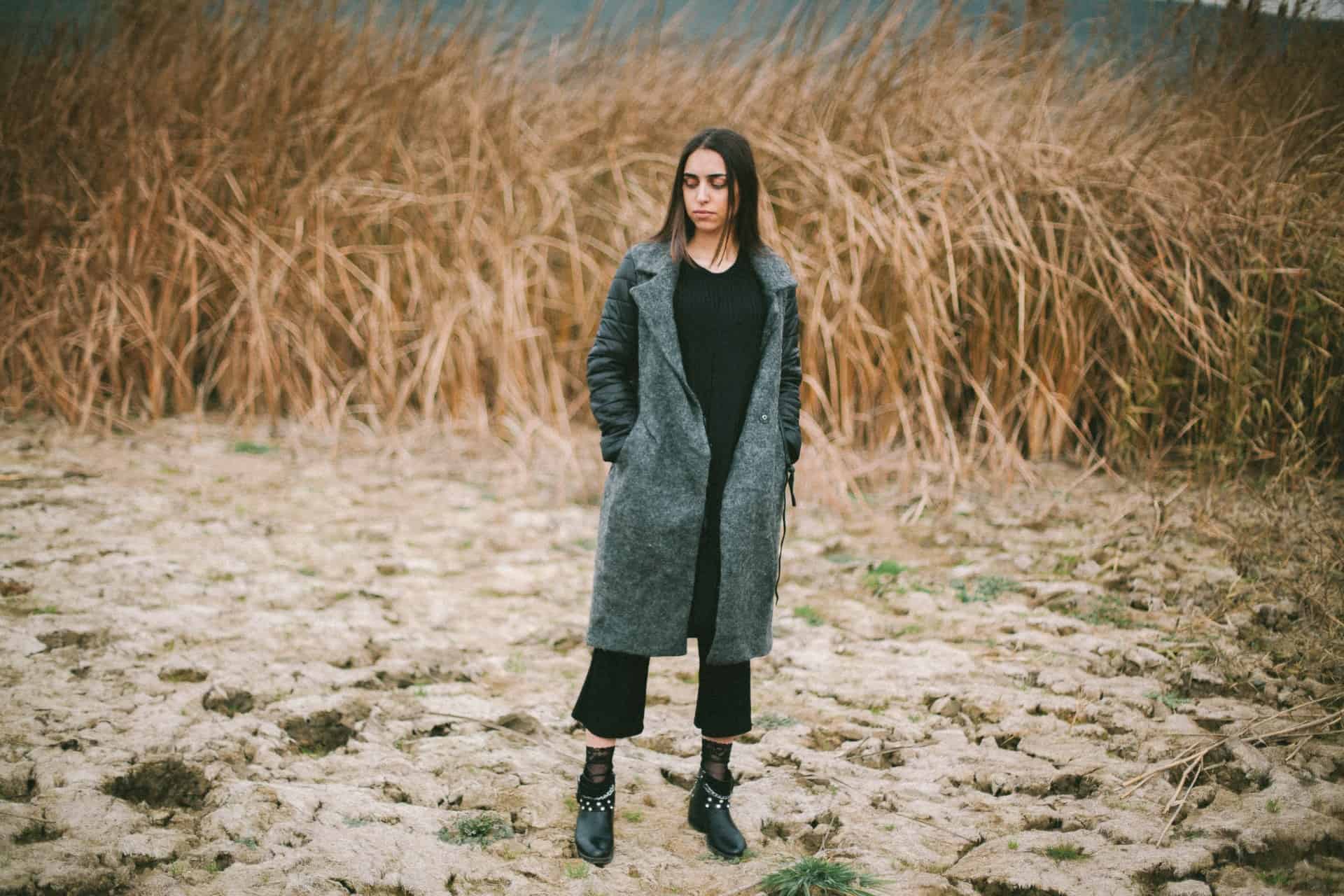brunettkvinna som står ensam i torrt fält