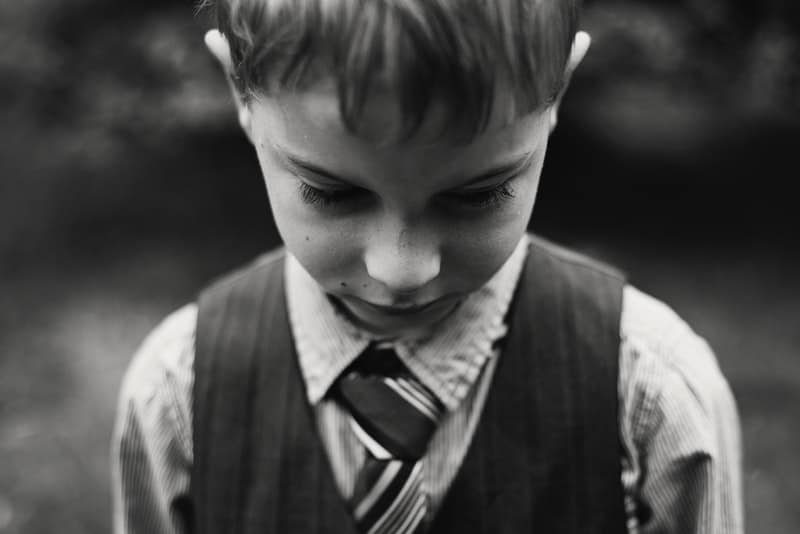 ett porträtt av ett sorgligt barn med en skjorta och slips