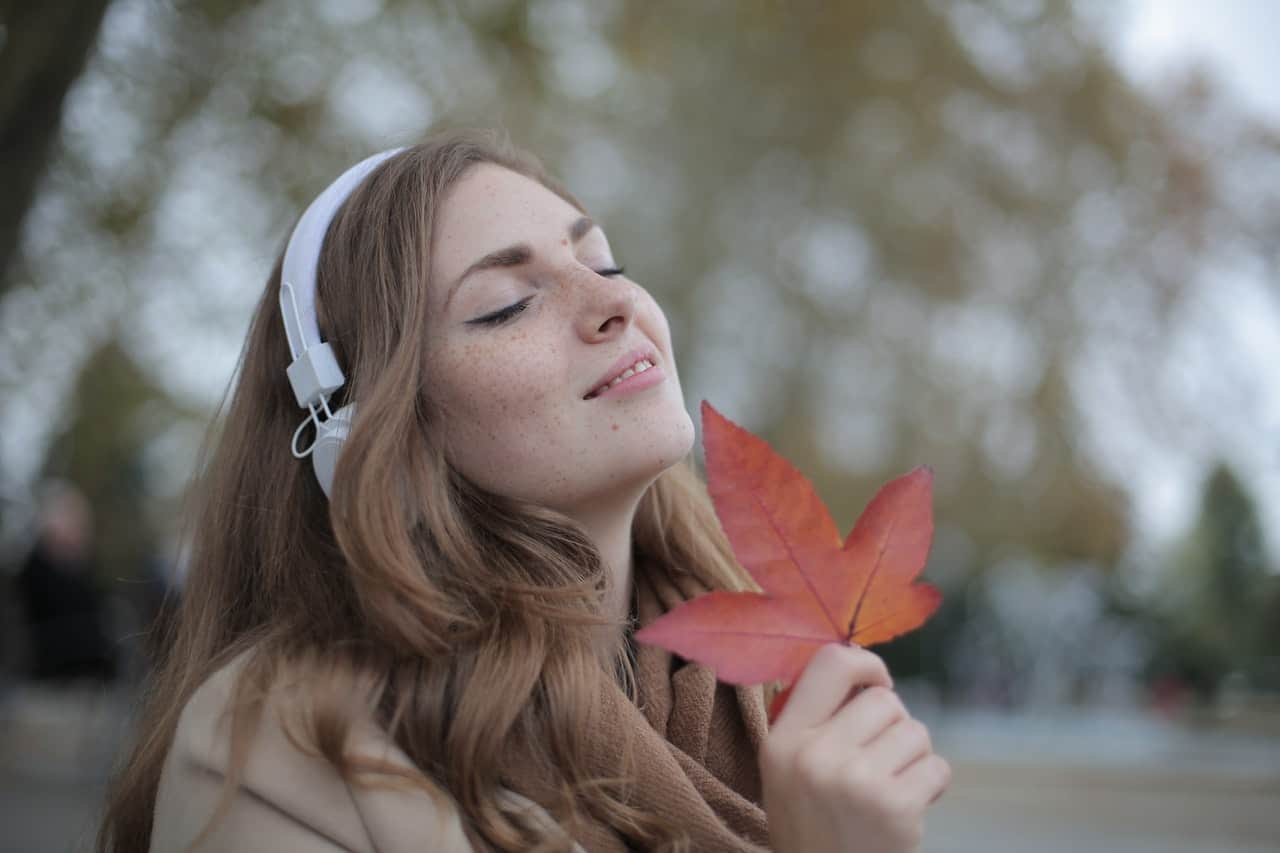 kvinna med hörlurar med färskt rött blad som lyssnar på musik
