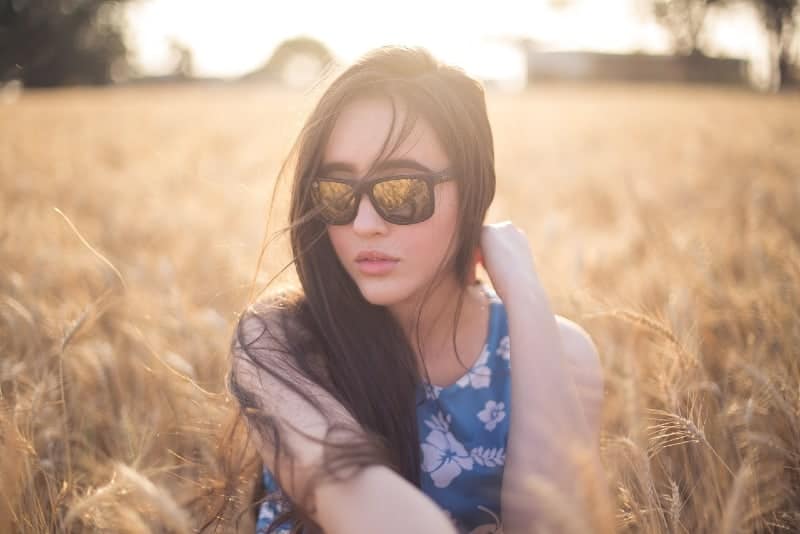 kvinna med solglasögon som sitter på gräset