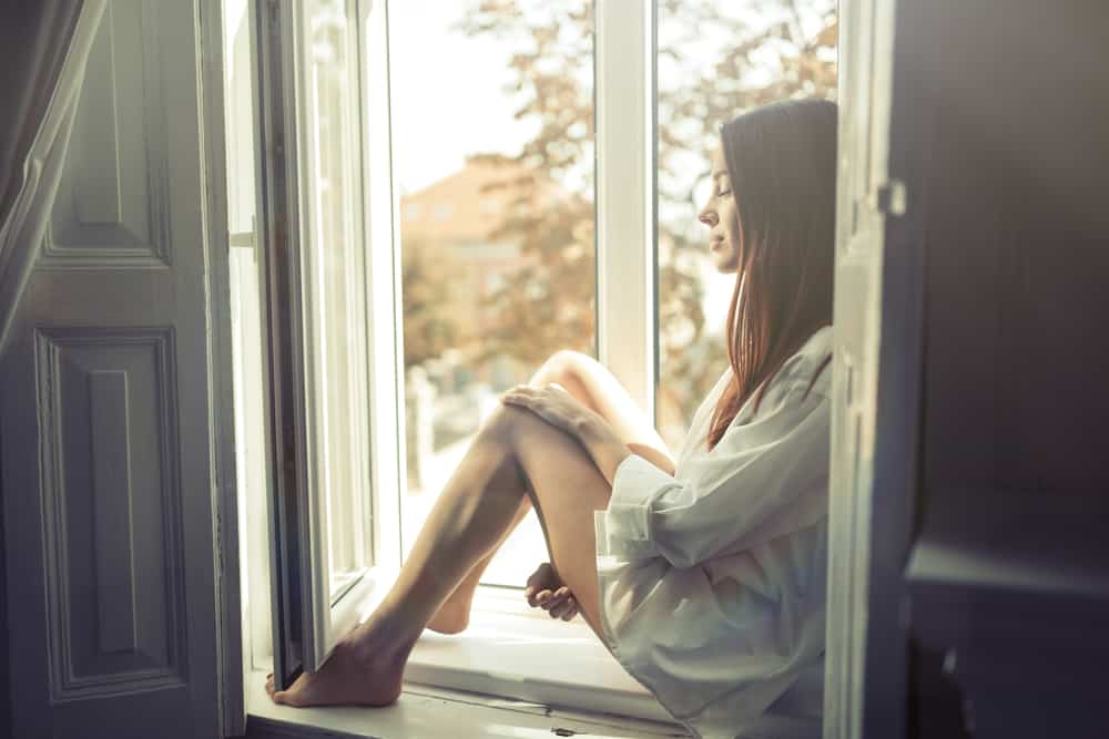 kvinna sitter ensam på fönstret och tänker