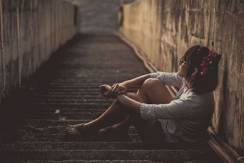 kvinna sitter ensam på steg och tänker