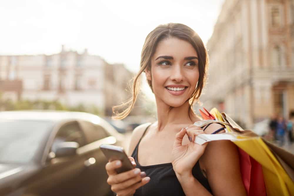 leende kvinna håller telefonen njuter av shopping