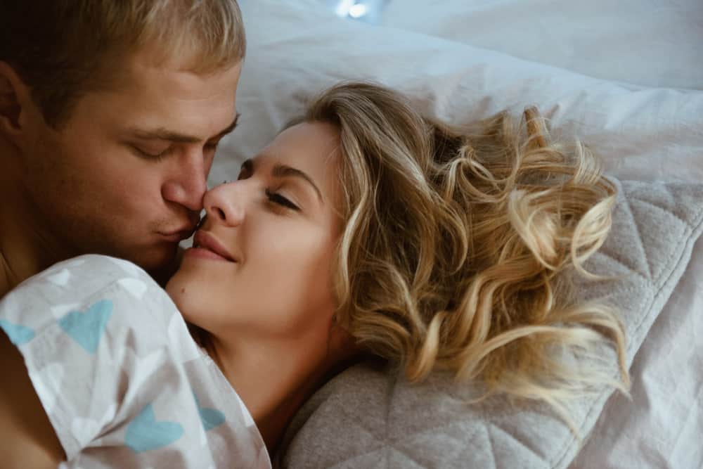 man kysser blond kvinna i sängen