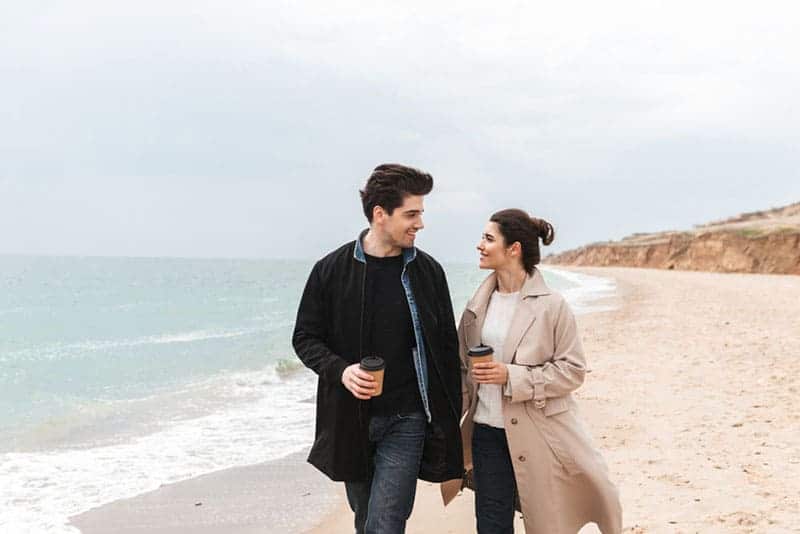 man och kvinna som dricker kaffe på stranden
