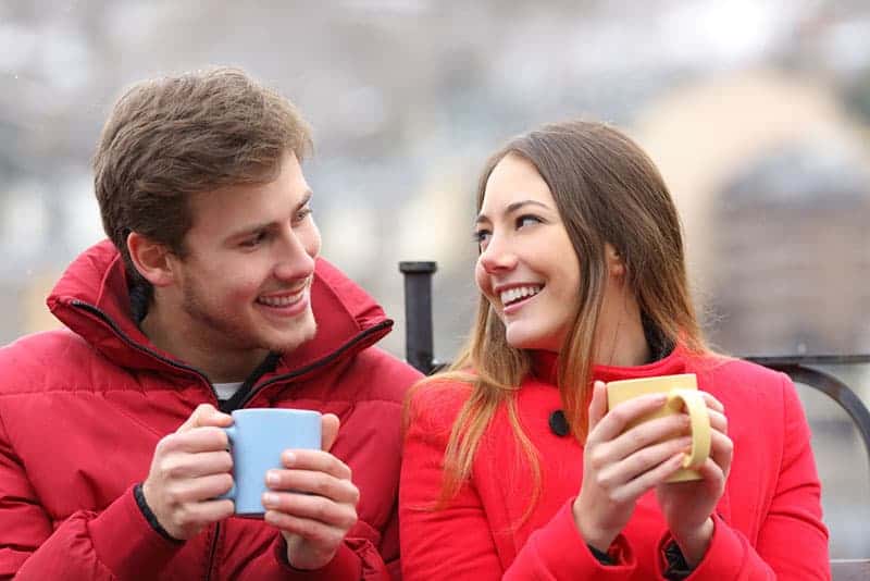 par i kärlek som håller koppar kaffe utomhus