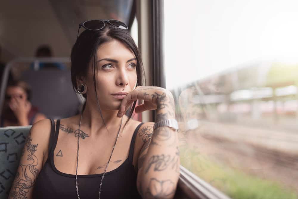 tatuerad kvinna i ett tåg som tittar ut genom fönstret