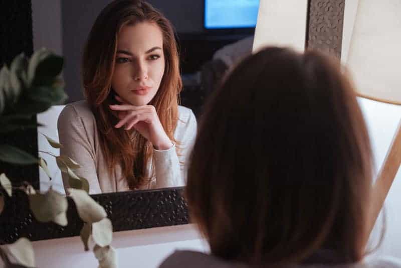 ung kvinna tittar på sig själv i spegeln