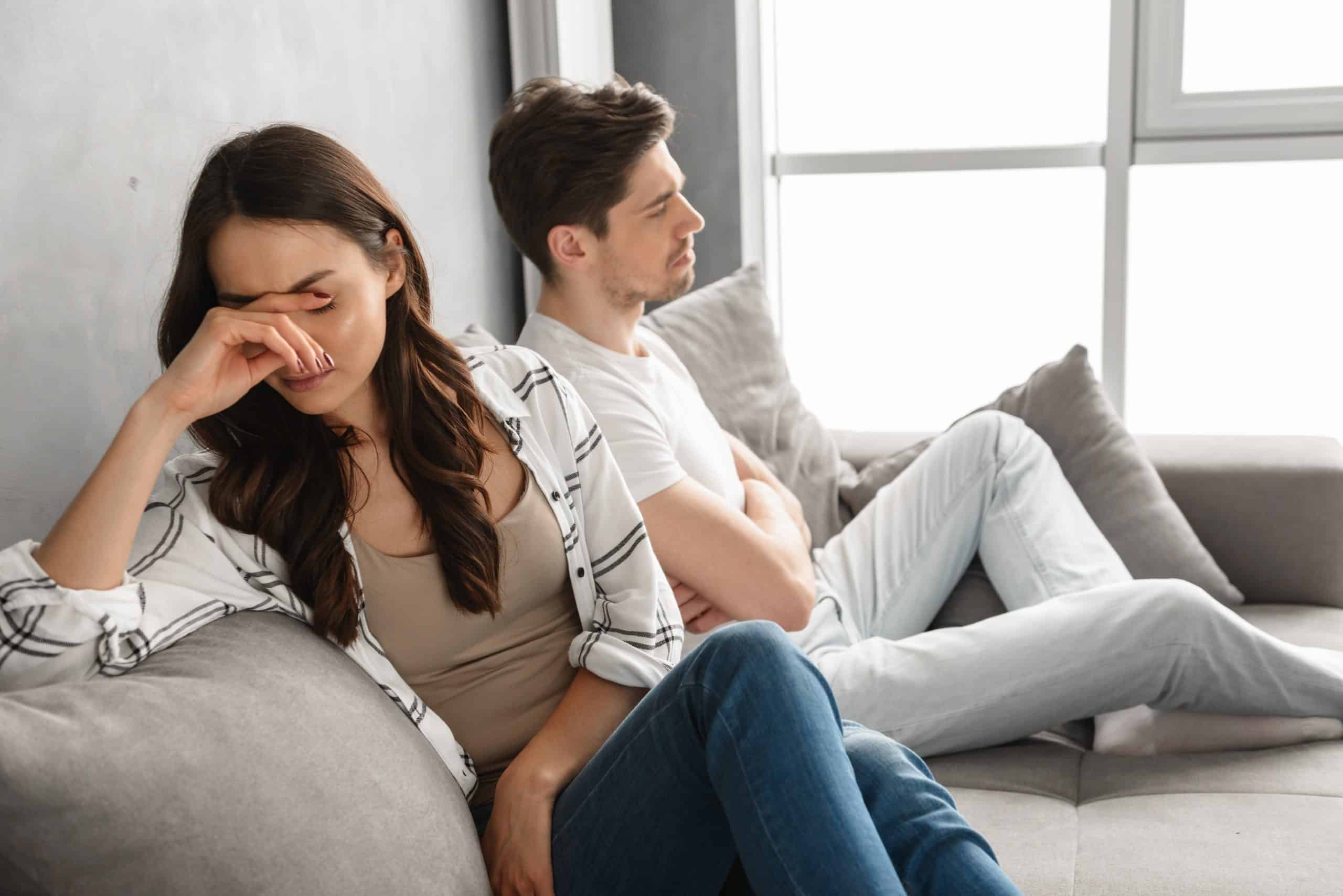Foto av besvikna par som tillsammans sitter på soffan hemma