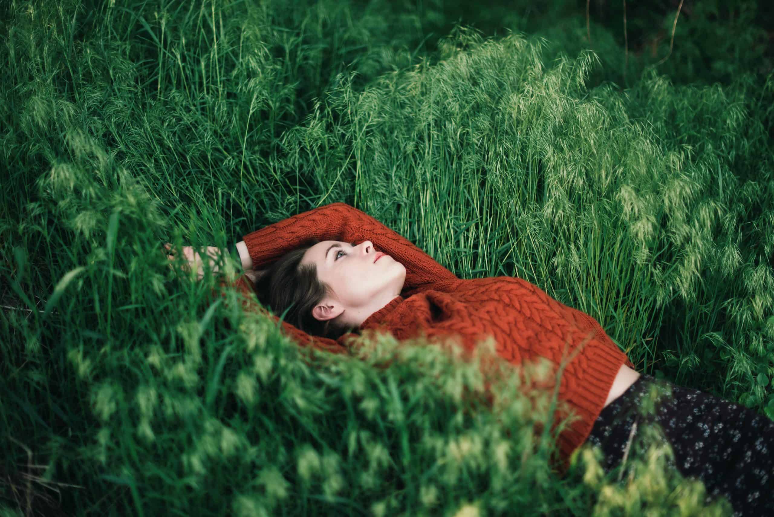 Fundersam kvinna som ligger på gräs