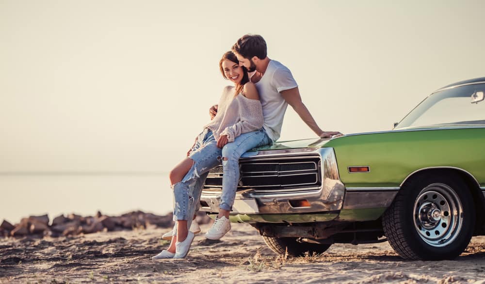 Romantiska par står nära den gröna retro bilen