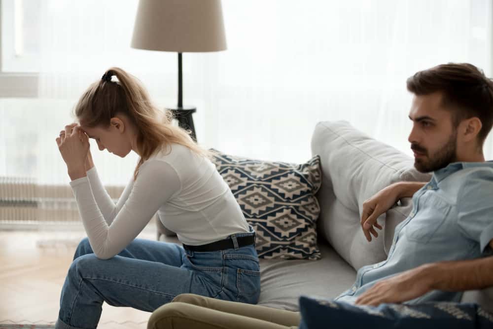 Trött olyckliga par som sitter isär på soffan och inte pratar