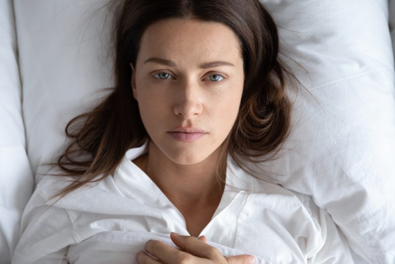 deprimerad upprörd ung kvinna ligga koppla av på vit kudde