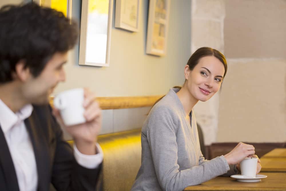 en kvinna med ett leende flirtar med en man på ett kafé