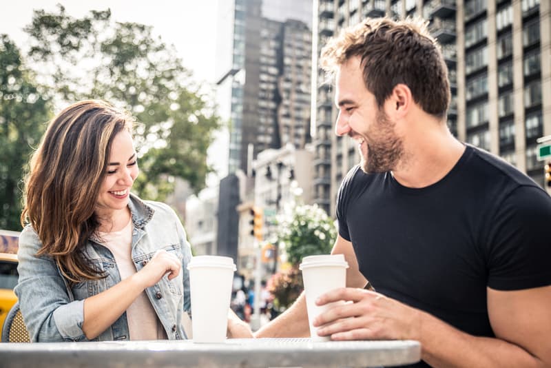 ett leende älskande par som dricker kaffe på terrassen och pratar