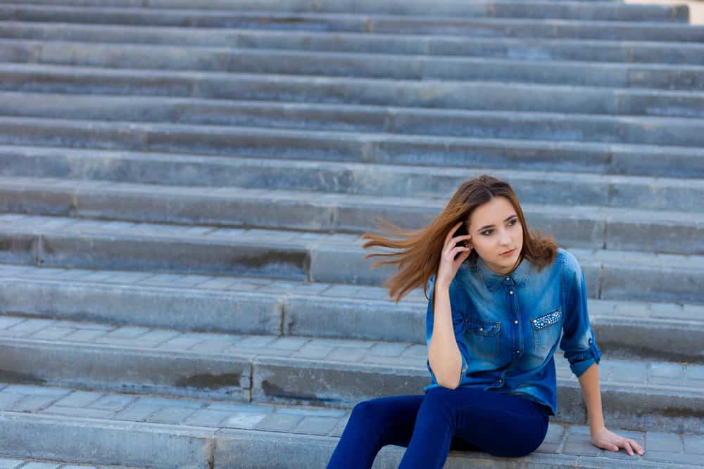 kvinna i denim som sitter på trappsteg ensam