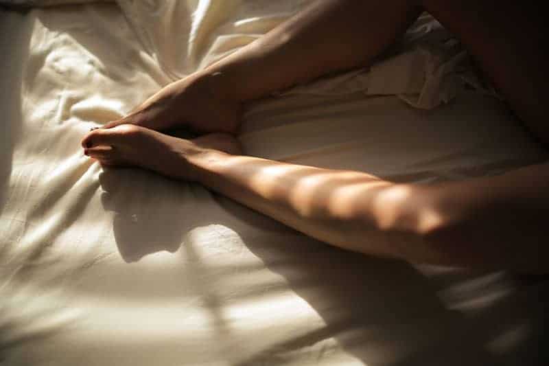 kvinna med nakna ben på sängen