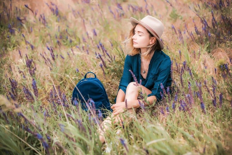 kvinna som bär hatt som sitter på gräset