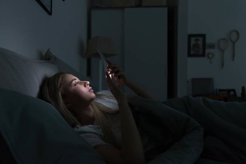 kvinna som skriver sin telefon på natten
